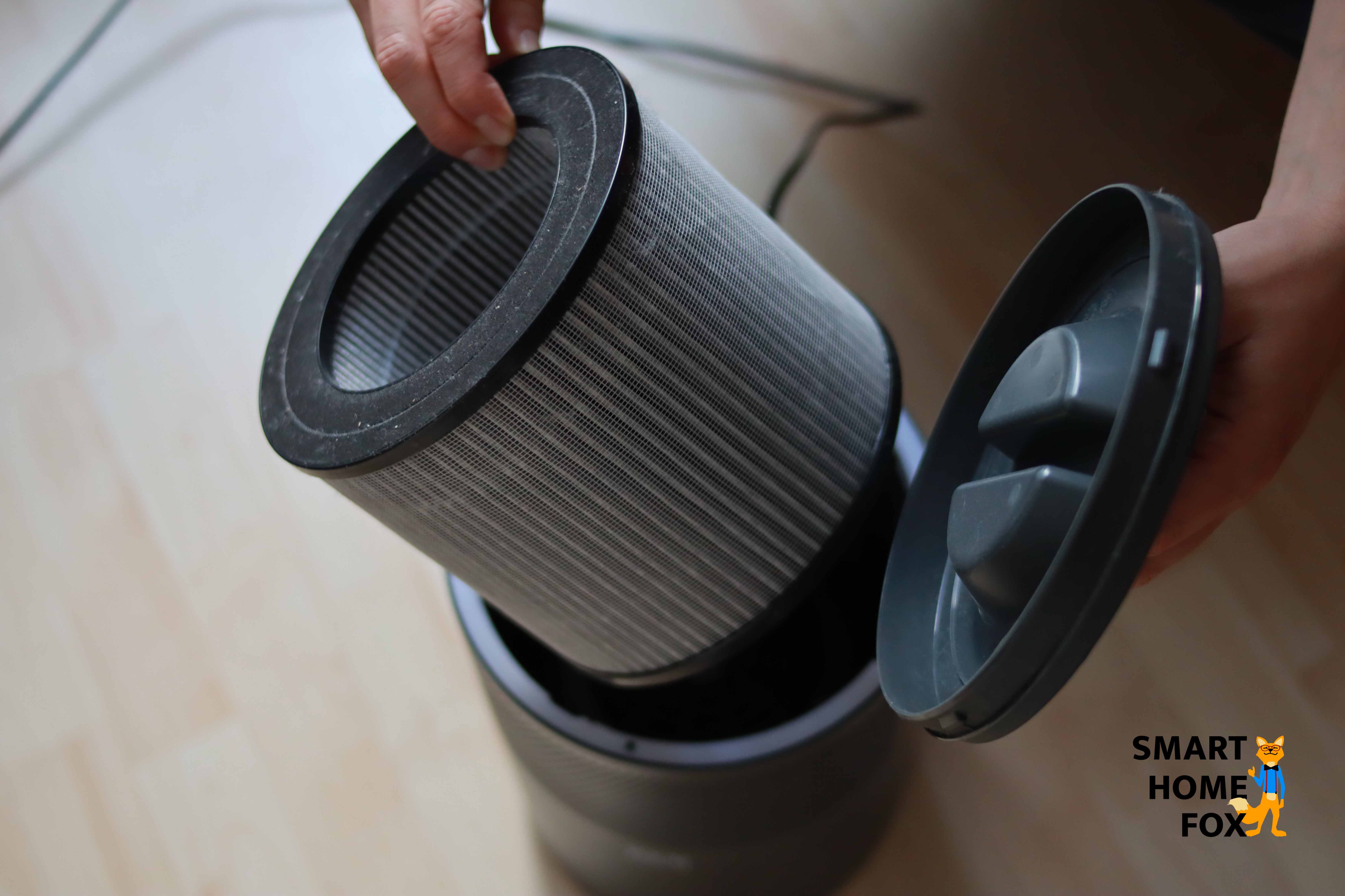 Ein Runder EPA-FIlter wird aus dem schwarzen Luftreiniger herausgeholt